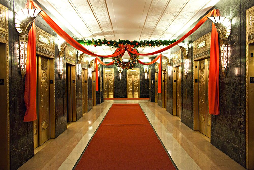 Holiday fabric and wreaths decorating a hallway of elevators